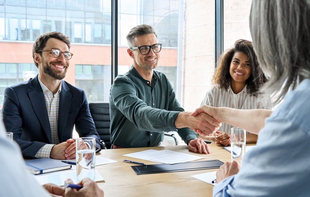 Profissional de comércio exterior em negociação internacional. Homem aperta mão de mulher em uma mesa de reunião. ead comercio exterior.