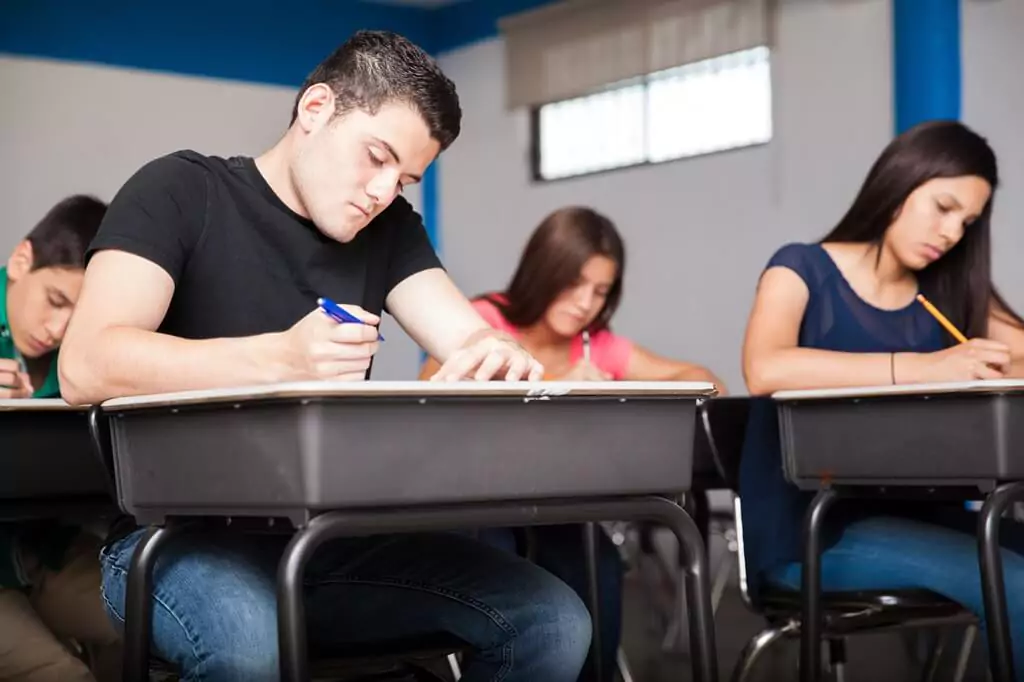 rapaz fazendo teste em sala de aula com outras pessoas