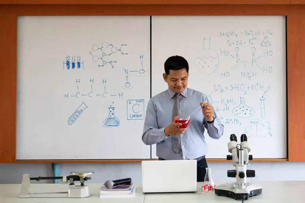 professor de química em sala de aula fazendo experimento