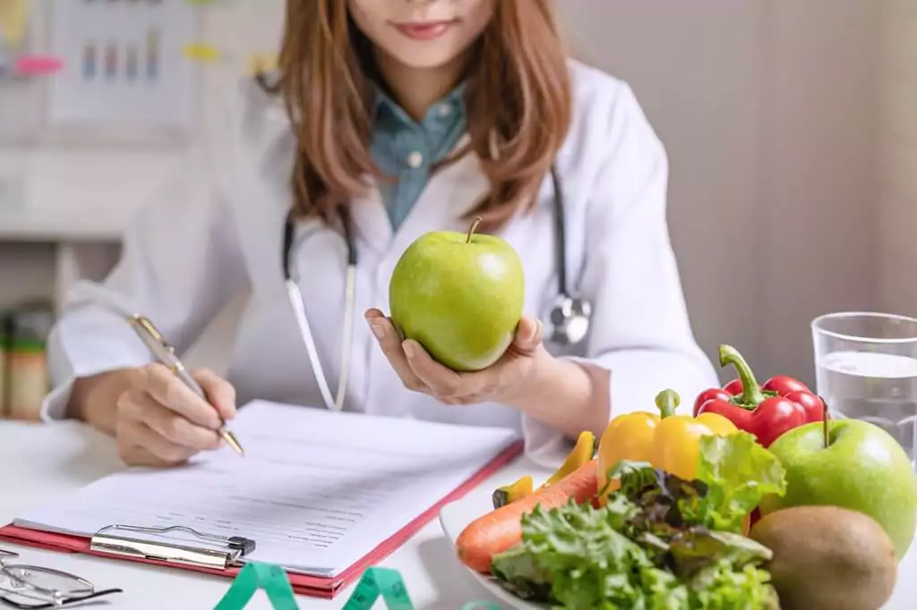 nutricionista segurando maçã e escrevendo relatório