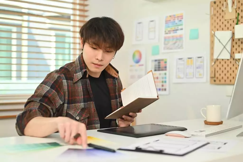 rapaz designer consultando informações de caderno