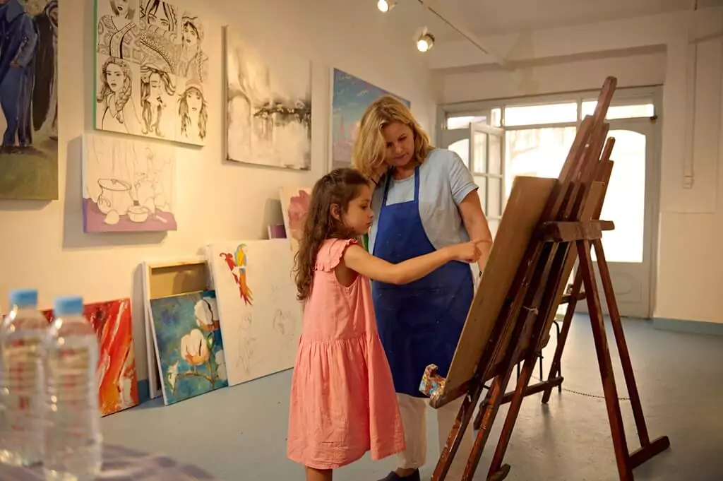 professora e criança em aula de arte