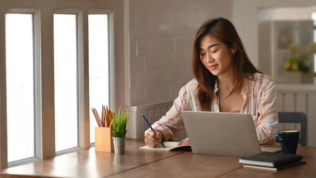 moça estudando com computador e caderno