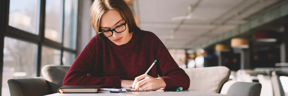 Jovem estudando para o enem em biblioteca.
