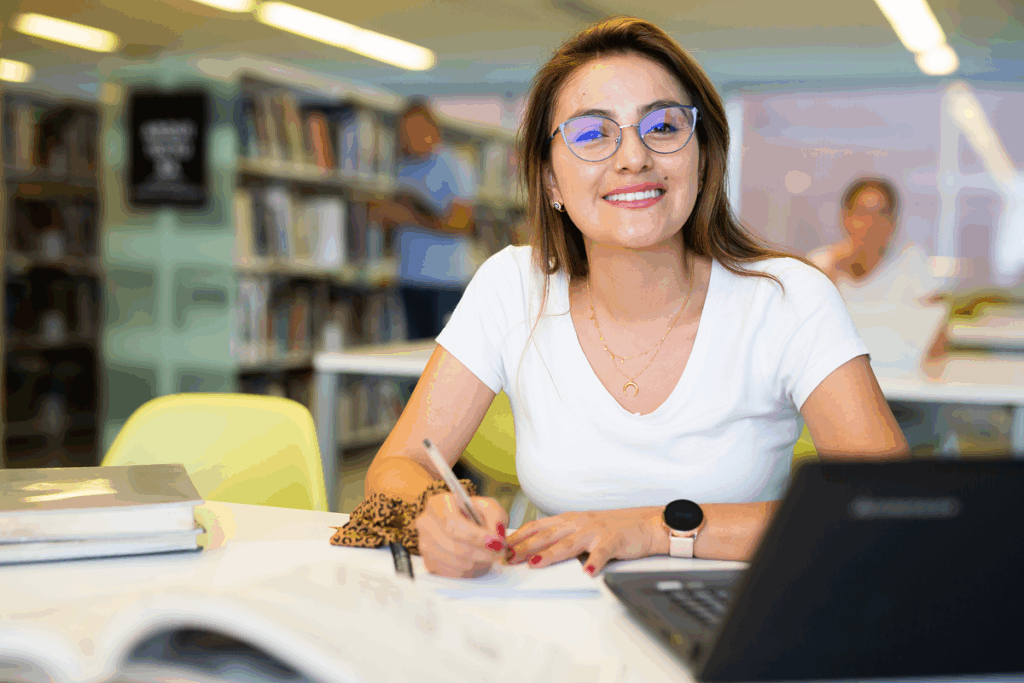 Mulher jovem estudando em biblioteca. Diferença entre EAD semipresencial e presencial.